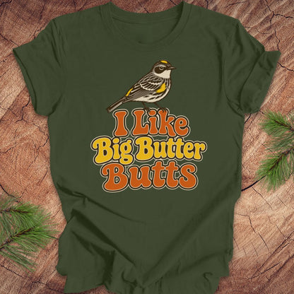Green t-shirt with a bird graphic and text 'I Like Big Butter Butts' on a wooden surface.