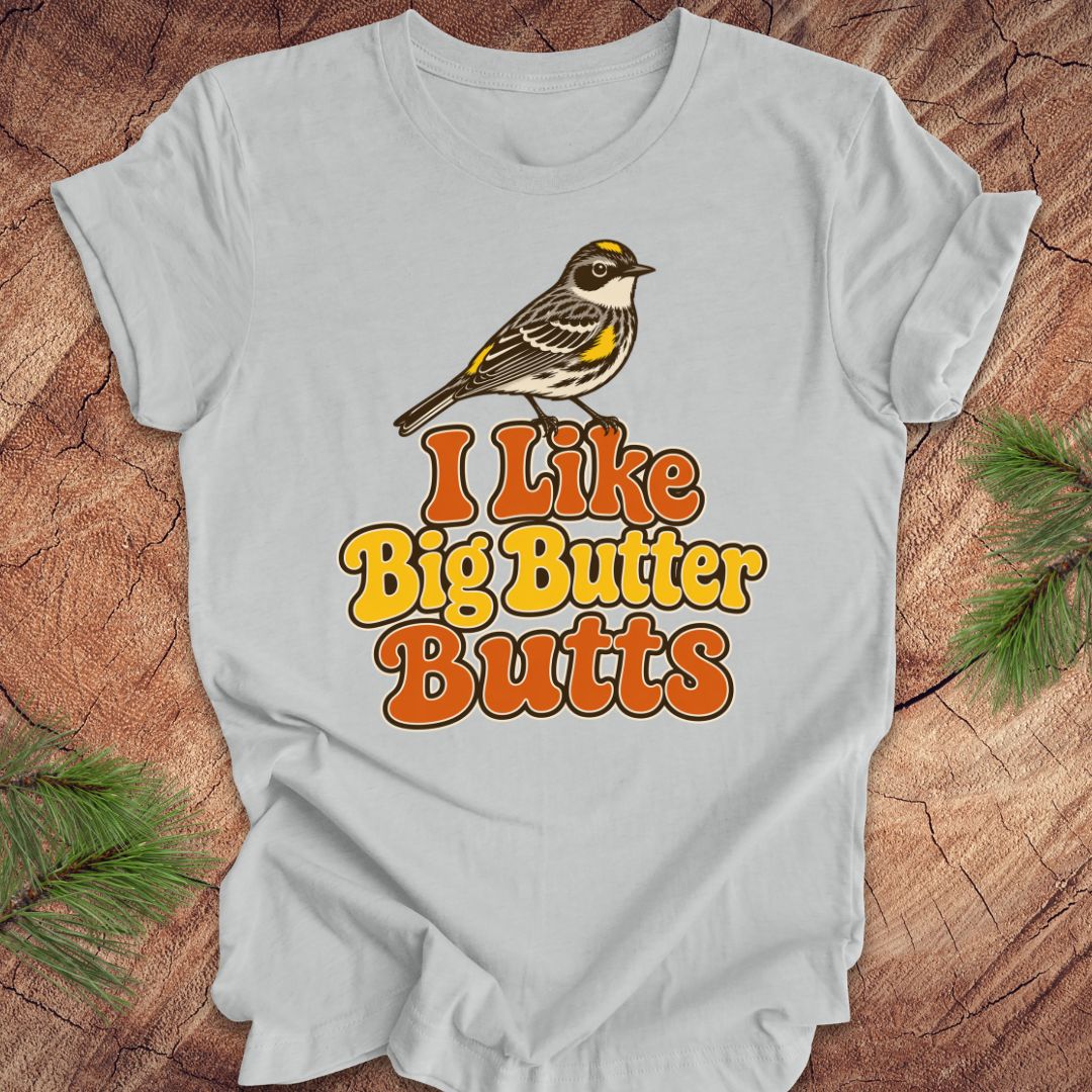 Gray t-shirt with a bird graphic and text 'I Like Big Butter Butts' on a wooden surface.