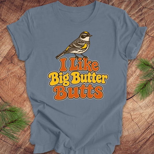 Blue t-shirt with a bird graphic and text 'I Like Big Butter Butts' on a wooden surface.