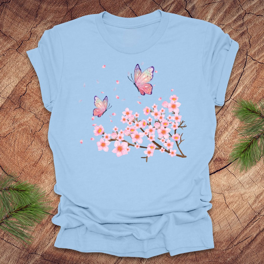 Light blue t-shirt with butterfly and cherry blossom design on a wooden surface