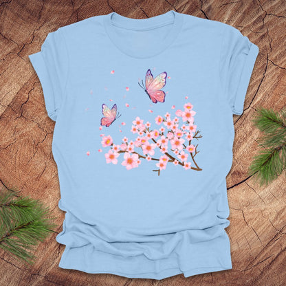 Light blue t-shirt with butterfly and cherry blossom design on a wooden surface
