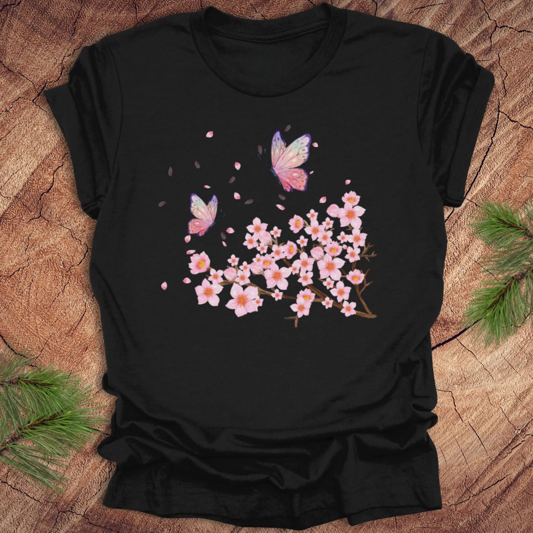 Black t-shirt with cherry blossom and butterfly design on a wooden surface