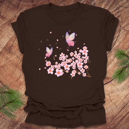 Brown t-shirt with cherry blossom and butterfly design on a wooden surface
