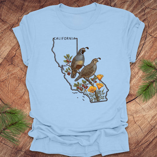 Baby blue t-shirt with California map and  quail and poppy design on a wooden surface