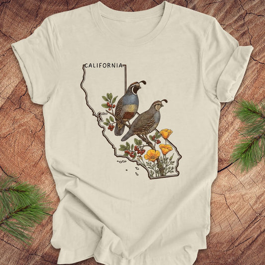 Beige t-shirt with California map design featuring quails and flowers on a wooden surface.