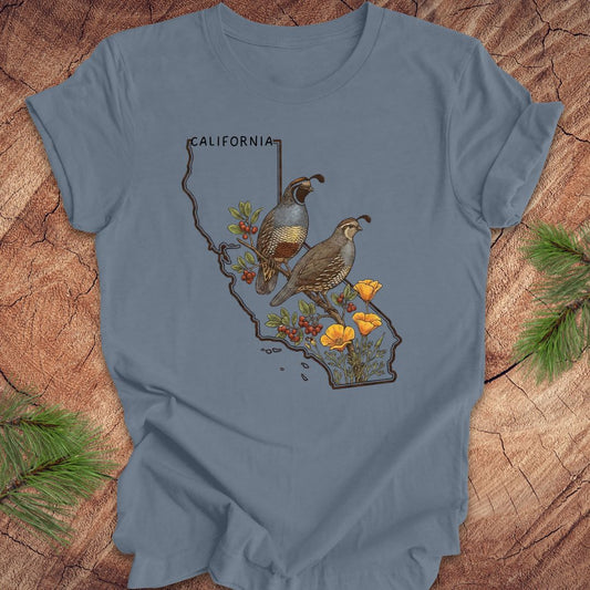 Blue t-shirt with California map design featuring quails and flowers on a wooden surface.