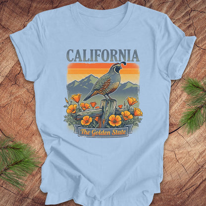 Light blue t-shirt with California-themed design featuring a bird and flowers on a wooden surface.