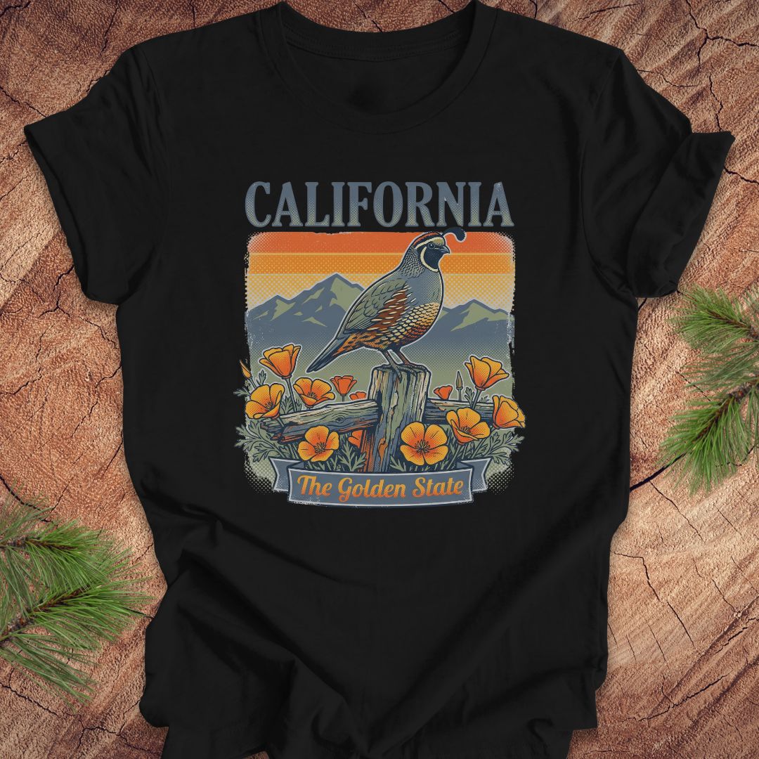 Black t-shirt with California-themed graphic featuring a quail, flowers, and mountains on a wooden surface.
