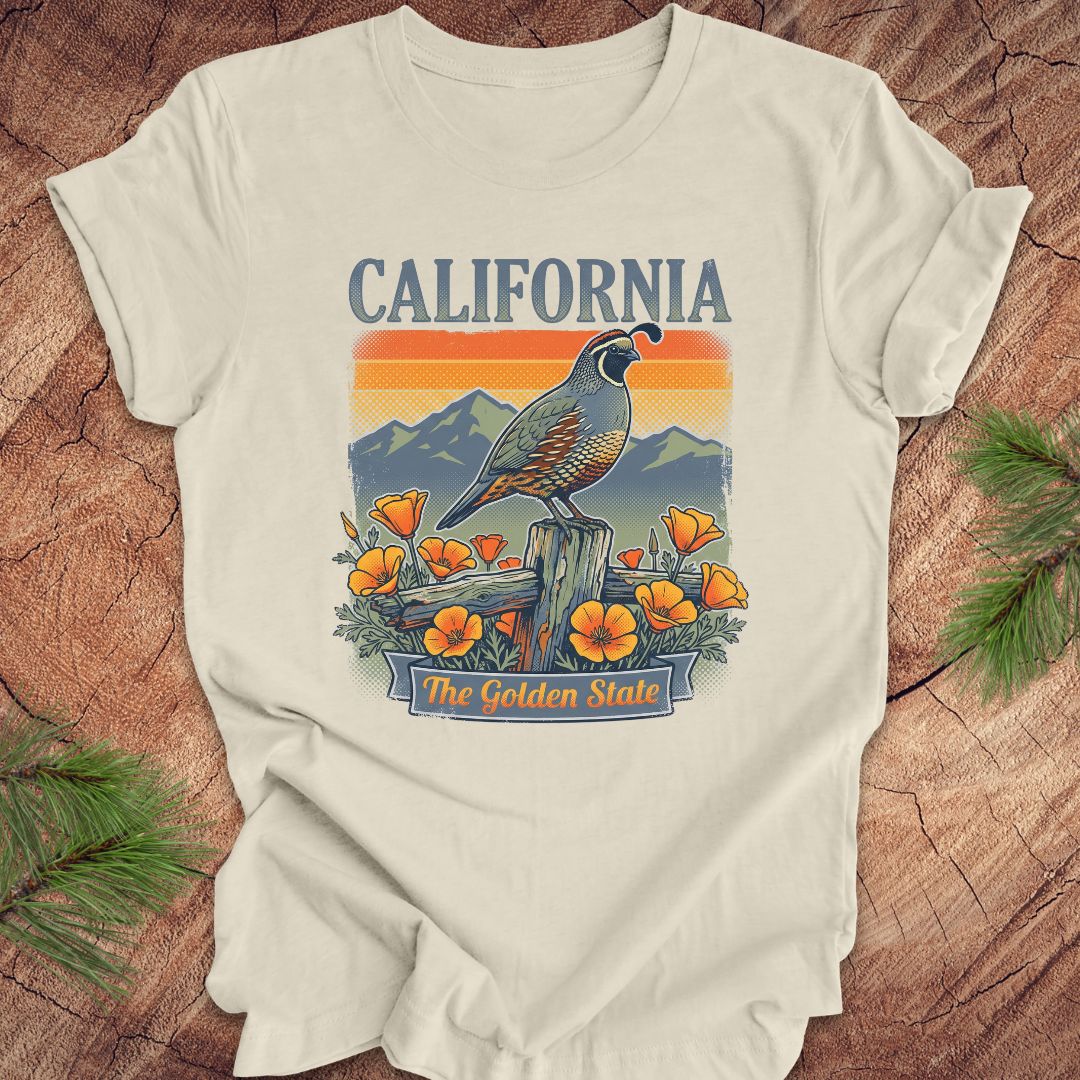 Beige t-shirt with California-themed design featuring a quail, mountains, and poppies on a wooden surface.