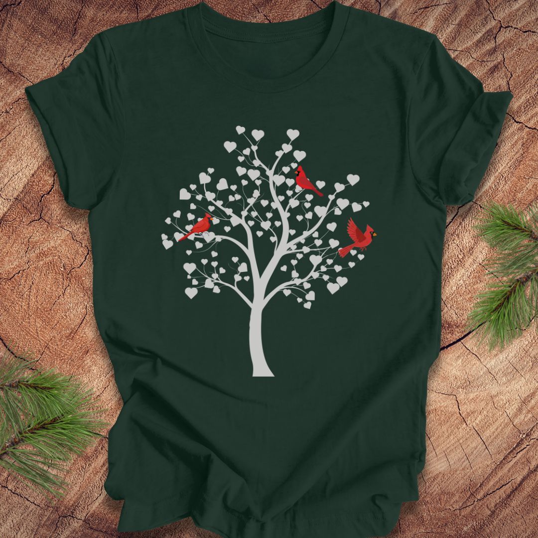 Green t-shirt with a tree and cardinal design on a wooden surface