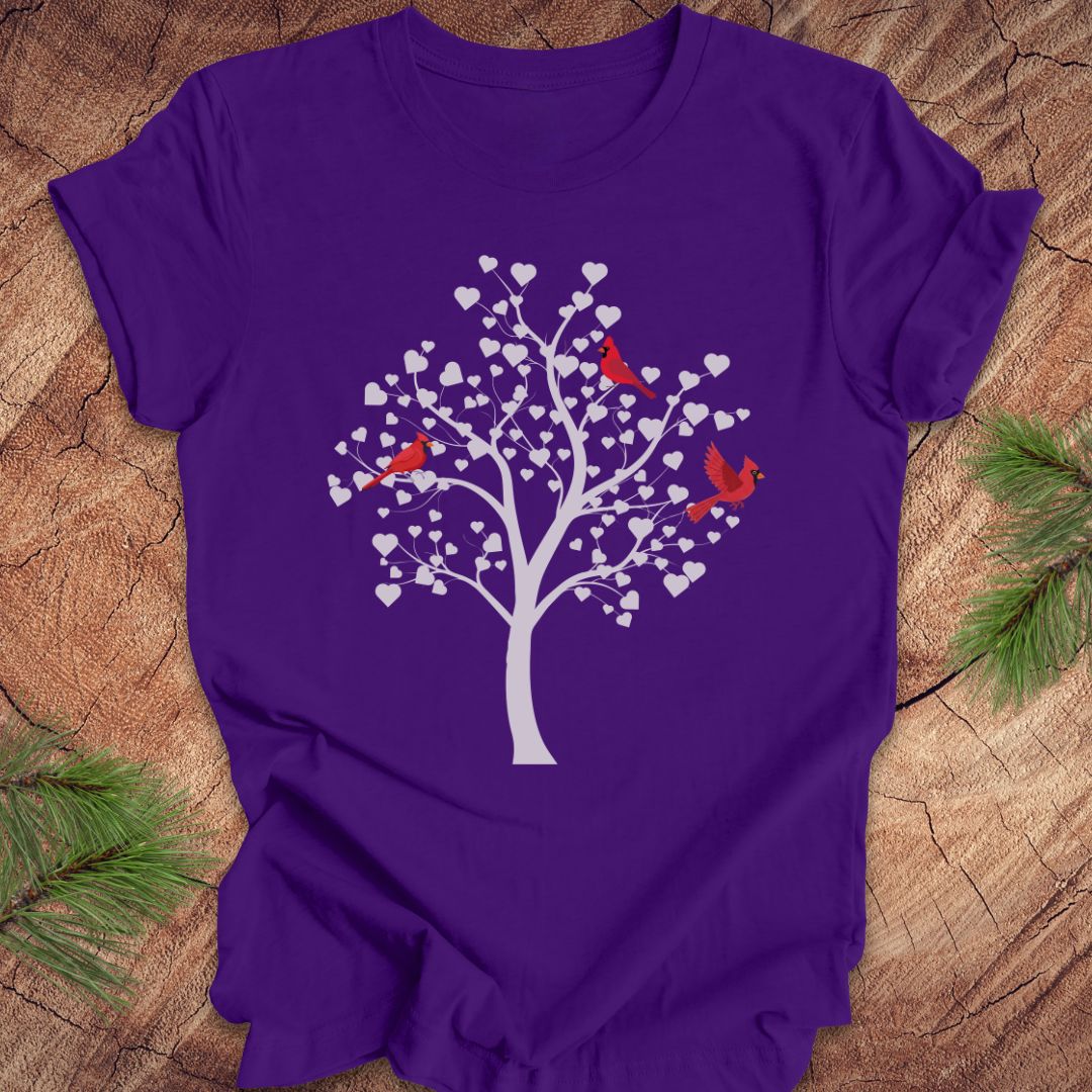 Purple t-shirt with a tree and birds design on a wooden surface