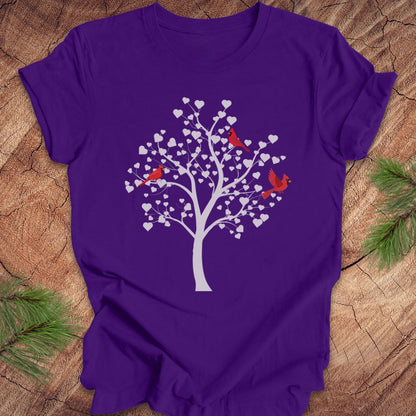 Purple t-shirt with a tree and birds design on a wooden surface