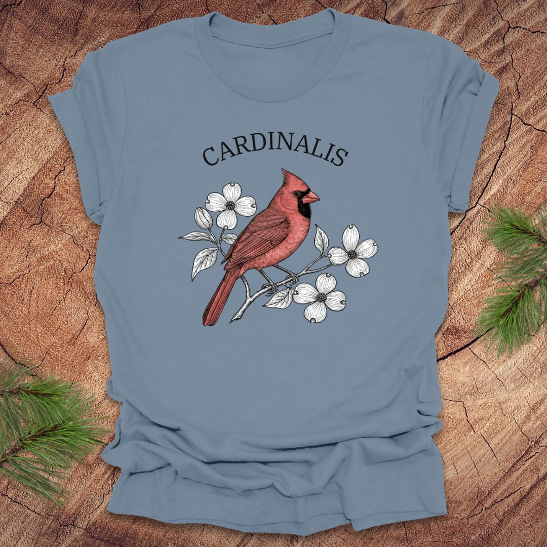 Steel blue t-shirt with a red cardinal bird design and scientific name text on a wooden surface