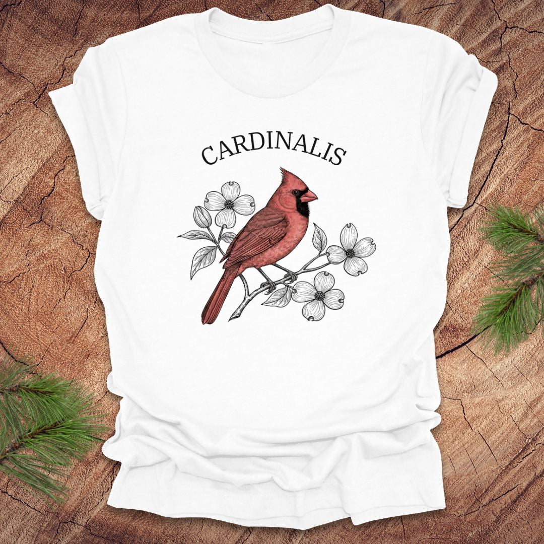 White t-shirt with a red cardinal bird design and scientific name text on a wooden surface