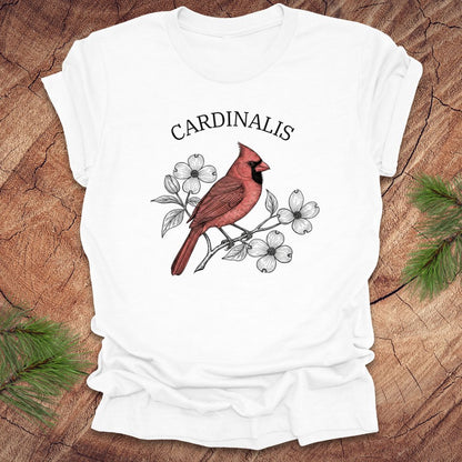 White t-shirt with a red cardinal bird design and scientific name text on a wooden surface