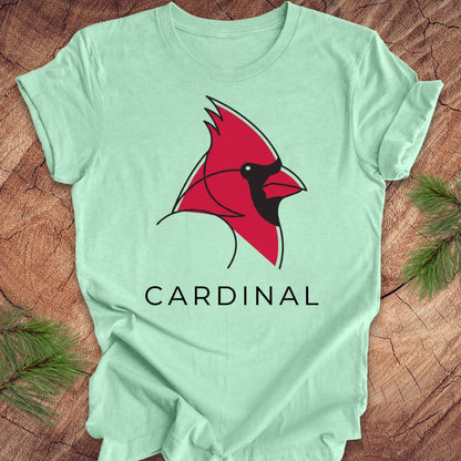Mint green t-shirt with a cardinal and text on a wood background.