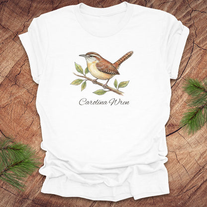 White t-shirt with a Carolina Wren illustration and text, 'carolina wren' on a wooden surface