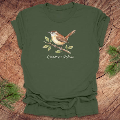 Green t-shirt with a Carolina Wren illustration and text, 'carolina wren' on a wooden surface