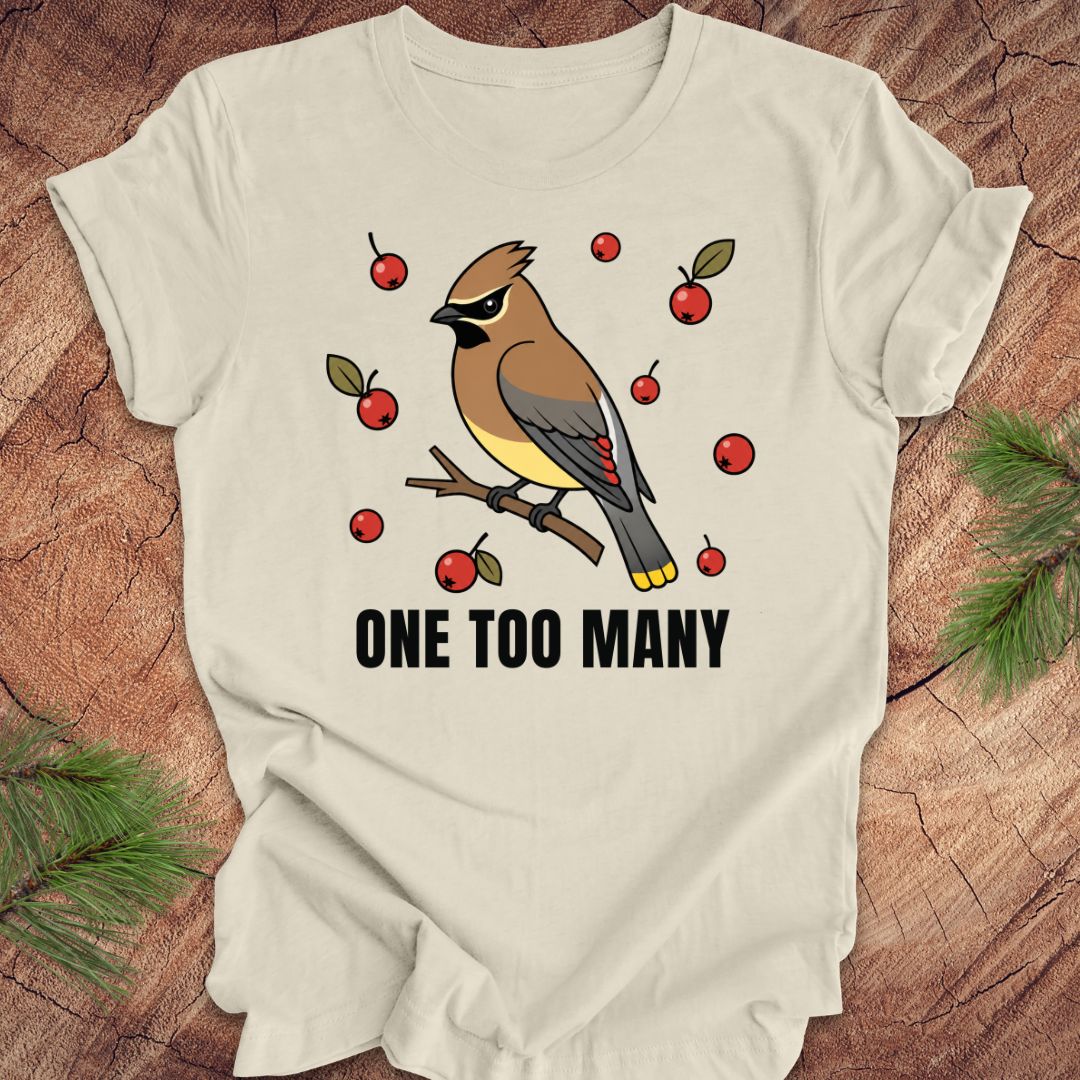 Beige t-shirt with a cedar waxwing bird and berry design on a wooden surface