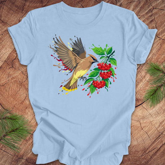Light blue t-shirt with a cedar waxwing bird and berry design on a wooden surface