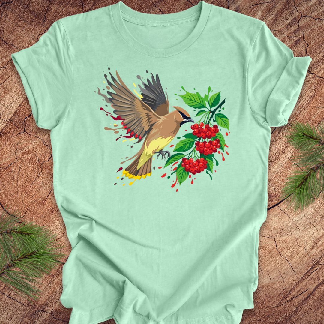 Mint green t-shirt with a cedar waxwing bird and berry design on a wooden surface