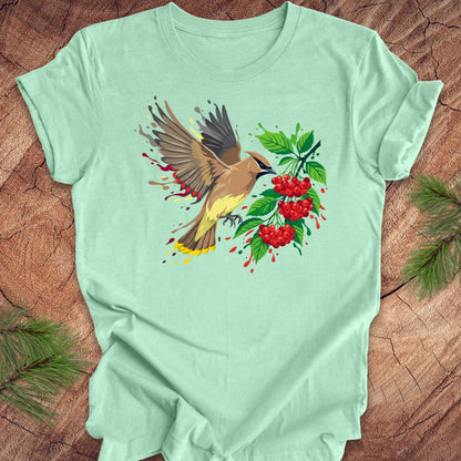 Mint green t-shirt with a cedar waxwing bird and berry design on a wooden surface
