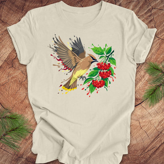 Beige t-shirt with a cedar waxwing bird and berry design on a wooden surface