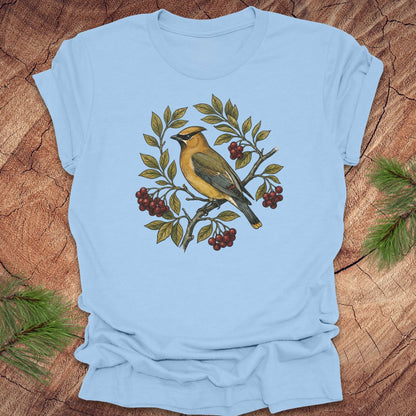 Light blue t-shirt with a cedar waxwing bird and leaf design on a wooden surface