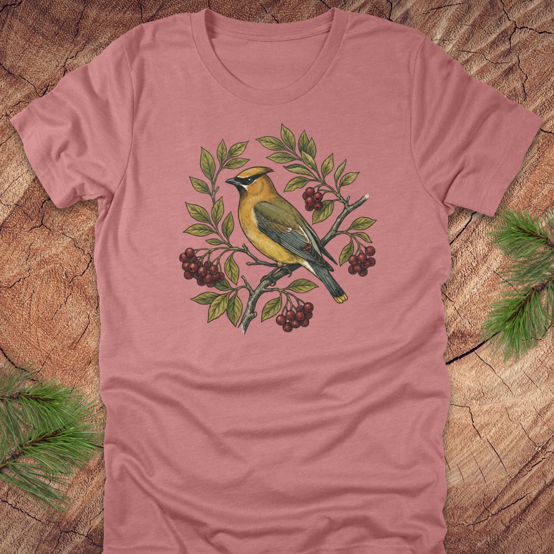 Mauve t-shirt with a cedar waxwing bird and leaf design on a wooden surface