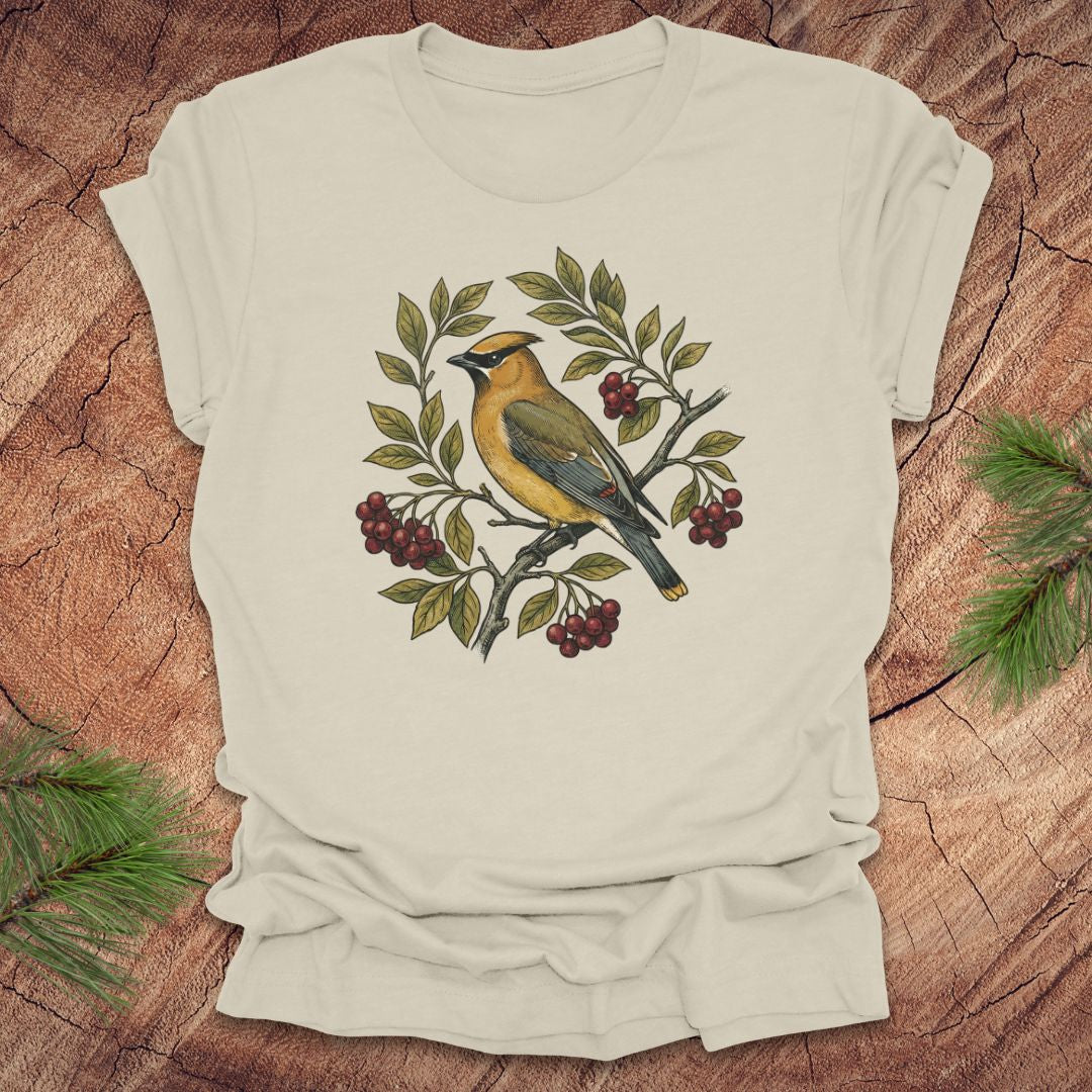 Beige t-shirt with a cedar waxwing bird and leaf design on a wooden surface