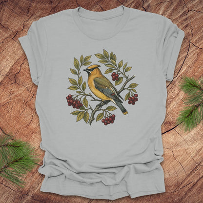 Silver t-shirt with a cedar waxwing bird and leaf design on a wooden surface