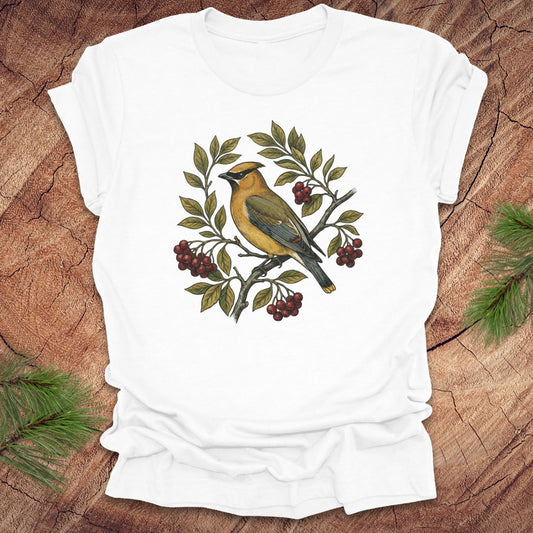White t-shirt with a cedar waxwing bird and leaf design on a wooden surface