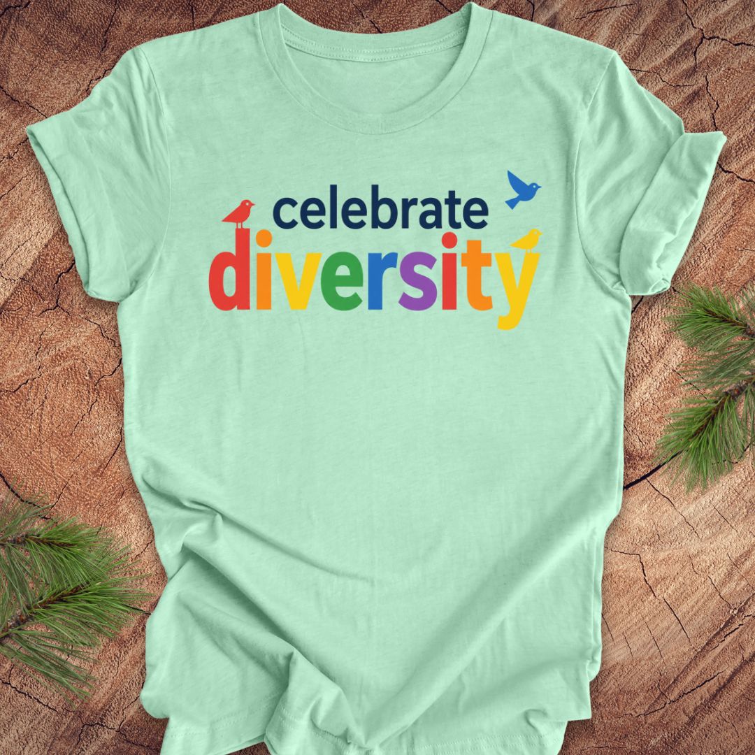 Light green t-shirt with 'celebrate diversity' text on a wooden surface