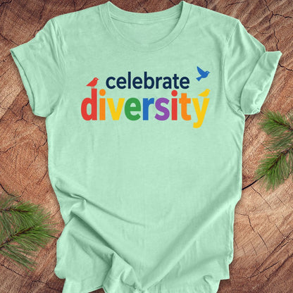 Light green t-shirt with 'celebrate diversity' text on a wooden surface