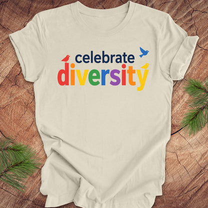 Beige t-shirt with 'celebrate diversity' text in colorful letters on a wooden surface.