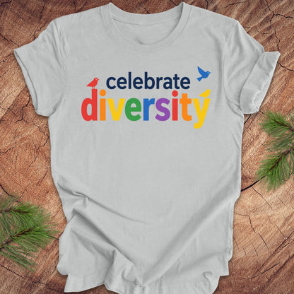 Gray t-shirt with 'celebrate diversity' text in colorful letters on a wooden surface.