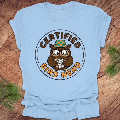 Light blue t-shirt with a 'Certified Bird Nerd' owl graphic on a wooden surface.