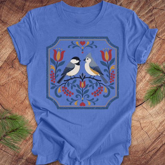 Blue t-shirt with chickadee, titmouse and floral design on a wooden surface