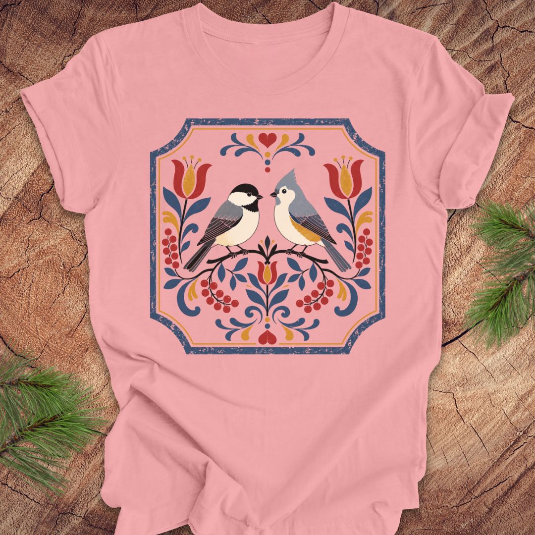 Pink t-shirt with chickadee, titmouse and floral design on a wooden surface