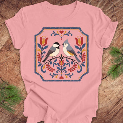 Pink t-shirt with chickadee, titmouse and floral design on a wooden surface