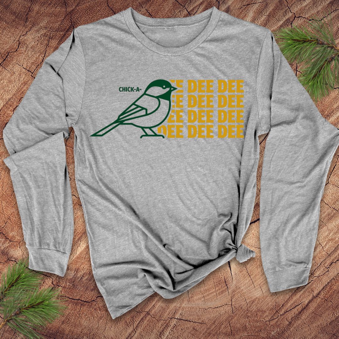 Gray long-sleeve shirt with a chickadee graphic and 'DEE DEE DEE' text on a wooden surface.