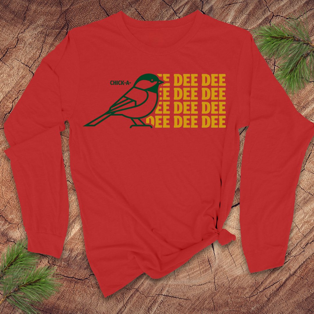 Red long-sleeve shirt with a chickadee graphic and 'DEE DEE DEE' text on a wooden surface.