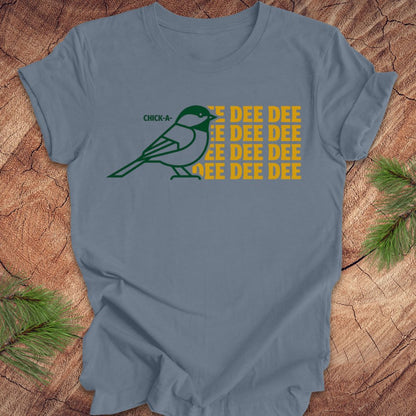 Blue t-shirt with a green chickadee graphic and 'DEE DEE DEE' text on a wooden surface.