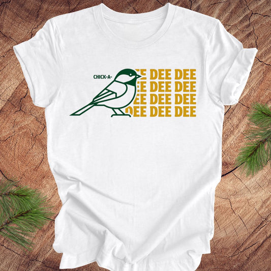 White t-shirt with a green chickadee graphic and 'DEE DEE DEE' text on a wooden surface.