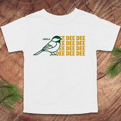 White toddler tshirt with a chickadee design and text on a wood background.