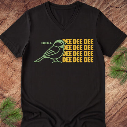 Black v-neck t-shirt with a green chickadee graphic and yellow text on a wooden surface.