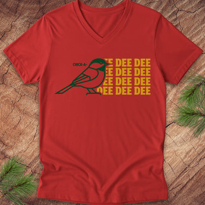 Red v-neck t-shirt with a green chickadee graphic and yellow text on a wooden surface.