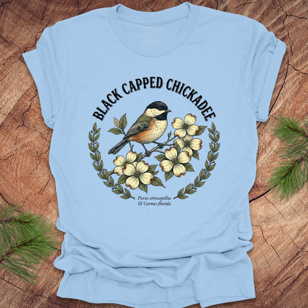 Light blue t-shirt with black-capped chickadee design on a wooden surface