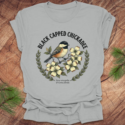 Gray t-shirt with black-capped chickadee design on a wooden surface