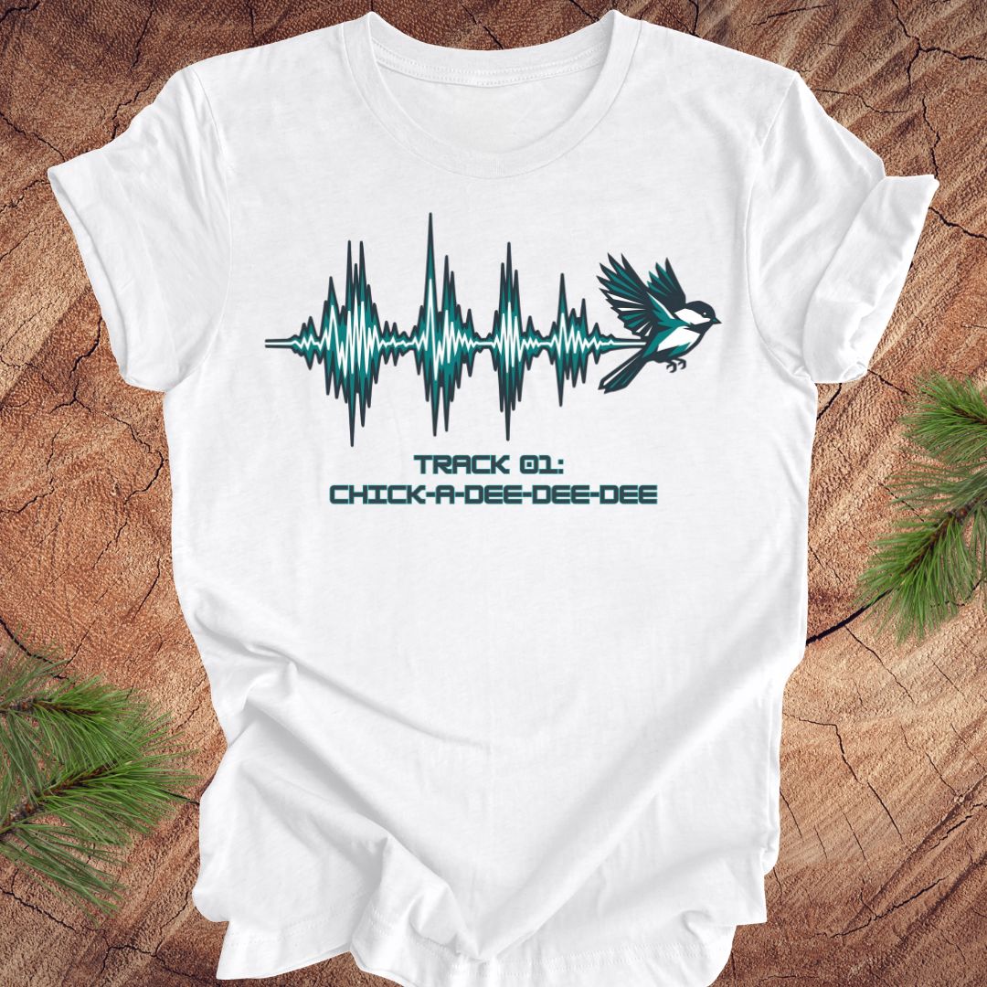White t-shirt with a chickadee and sound wave design on a wooden surface